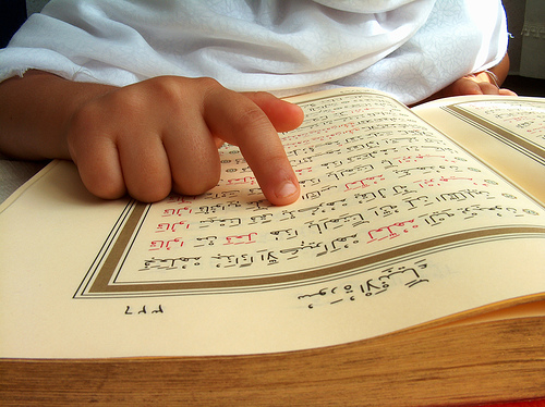 A child point his finger at the Mushaf - The One Who Struggles in Recitation